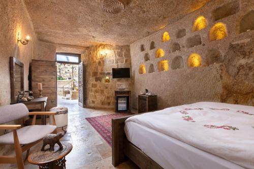 a bedroom with a bed and a chair and a fireplace at Kayata Cave Suites Special Class in Urgup