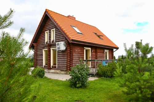 a small wooden house with an orange roof at Rąstinis namelis poilsiui in Karklė