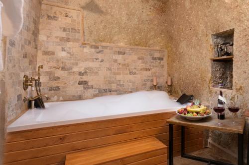 a bath tub with a bowl of fruit on a table at Kayata Cave Suites Special Class in Urgup