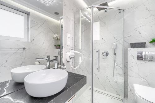 a white bathroom with a sink and a shower at Silver Apartments in Świnoujście
