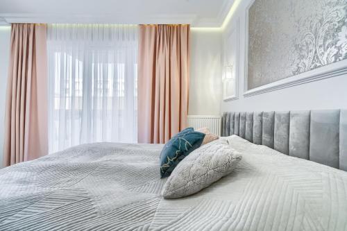 a bed with a pillow on it with a window at Silver Apartments in Świnoujście