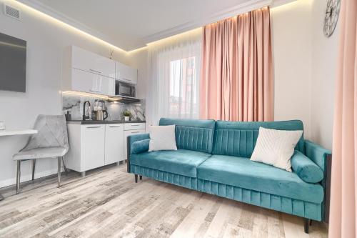 a living room with a blue couch and a kitchen at Silver Apartments in Świnoujście