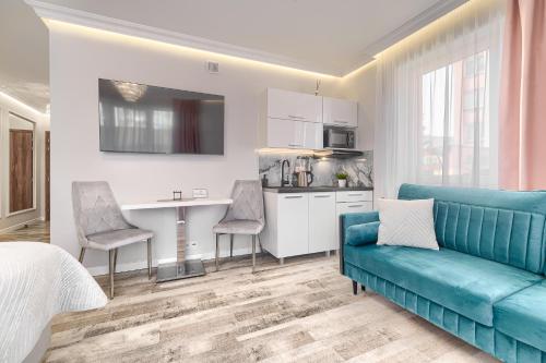 a living room with a blue couch and a kitchen at Silver Apartments in Świnoujście