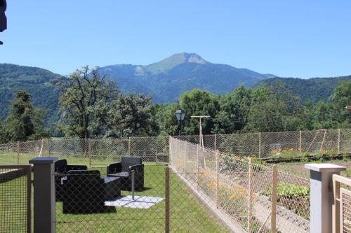 a fence with two chairs in a garden with mountains in the background at Chez Gilles et Christine in Mieussy