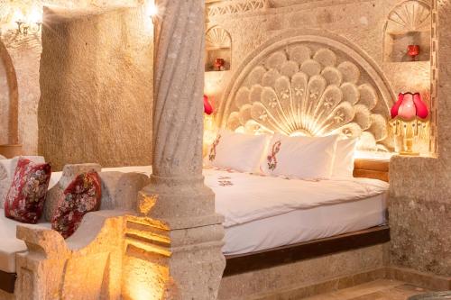 a bedroom with a bed with an ornate headboard at Kayata Cave Suites Special Class in Urgup