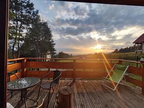 a deck with a table and chairs and the sunset at Domek u Basi in Czorsztyn