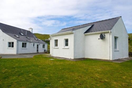 a couple of white buildings with a grass yard at 7B Ardroil in Uig