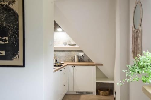 a small kitchen with white cabinets and a staircase at Złota#208 in Złota