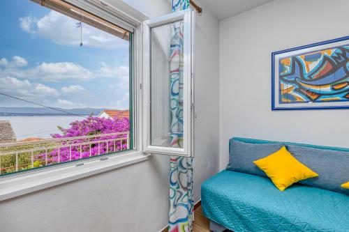 ventana con sofá azul y vistas al agua en Award winning Garden Apartment with large Terrace and amazing Seaview, en Bol