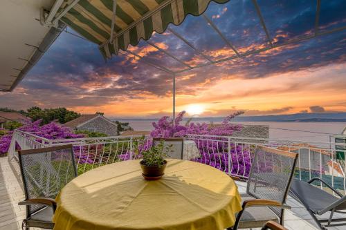 una mesa y sillas en un balcón con puesta de sol en Award winning Garden Apartment with large Terrace and amazing Seaview, en Bol