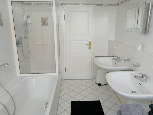 a white bathroom with a sink and a shower at Ferienwohnung Frankfurt in Neu-Anspach