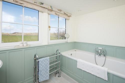 a bathroom with a tub and a sink and windows at Ardlarach Lodge in Cullipool