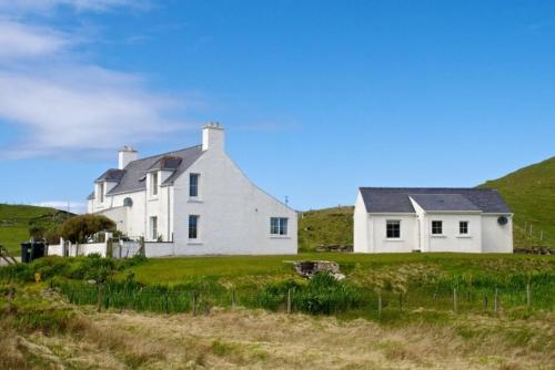 a large white house on a grassy field at 7A Ardroil in Uig