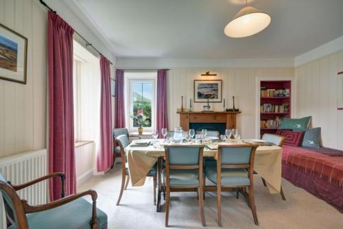 a dining room with a table and chairs and a bed at 7A Ardroil in Uig