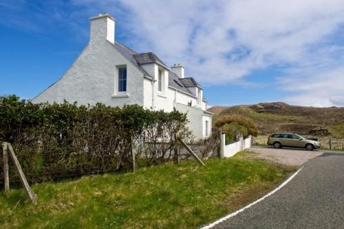 a car parked in front of a white house at 7A Ardroil in Uig