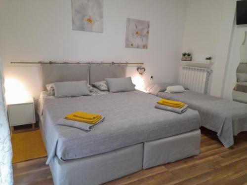 two beds in a bedroom with yellow towels on them at Cristel malpensa room in Cardano al Campo