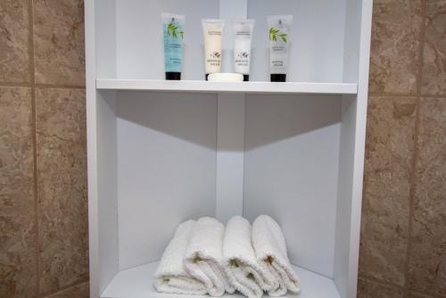 a white shelf with two mittens and products in a bathroom at Braemore Cottage in Tarbert
