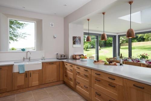 uma cozinha com paredes brancas e armários e janelas de madeira em Beltie Lodge em Borgue