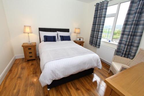 een slaapkamer met een groot bed en een raam bij Tulloch House in Lochboisdale