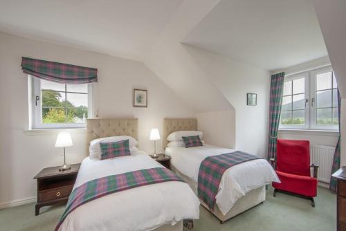 a bedroom with two beds and a red chair at Branter Lodge in Strachur