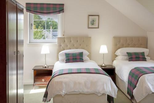 a bedroom with two beds and two lamps and a window at Branter Lodge in Strachur
