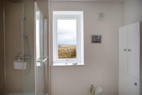 La salle de bains est pourvue d'une douche et d'une fenêtre. dans l'établissement Ceannard Cottage, à Howmore