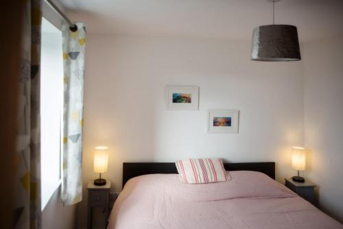 - une chambre avec un lit avec une couverture rose et 2 lampes dans l'établissement Ceannard Cottage, à Howmore