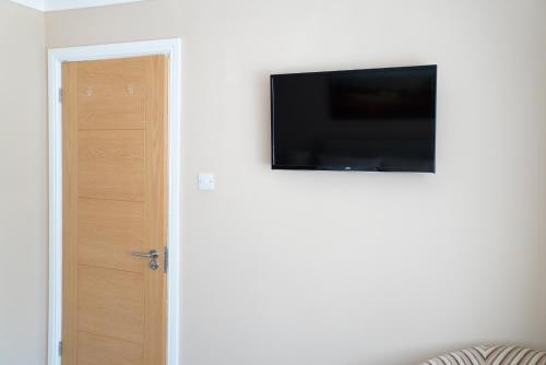 a flat screen tv on a wall next to a door at The Cedars in West Clandon