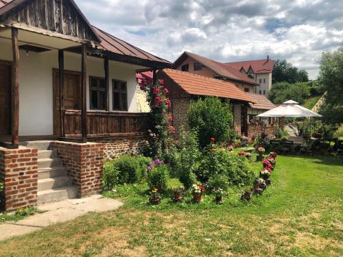 a house with a garden with flowers in the yard at Old Court in Curtea de Argeş