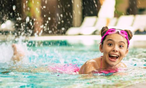 a little girl swimming in a swimming pool at Holiday Inn & Suites St. Cloud by IHG in Saint Cloud
