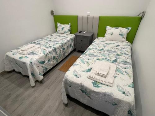 two twin beds in a room with green headboards at Ria Studios in Olhão