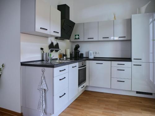 a kitchen with white cabinets and black counter tops at Appartement SCHILLER I - Erfurt Zentrum in Erfurt
