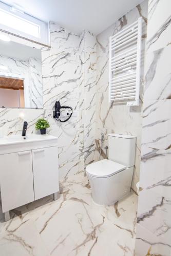 a bathroom with a white toilet and a marble wall at La Casona 1930 in Mazaricos