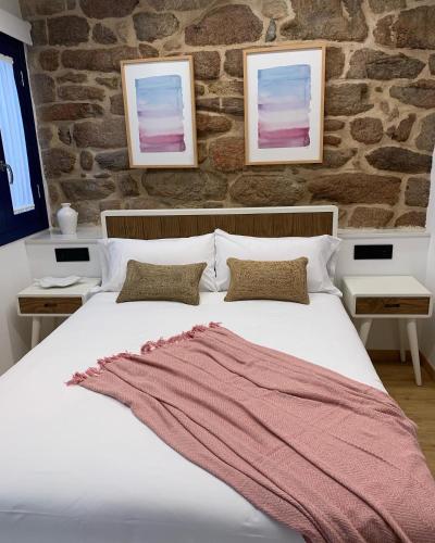 a bedroom with a white bed with a brick wall at Mar De Muros in Muros