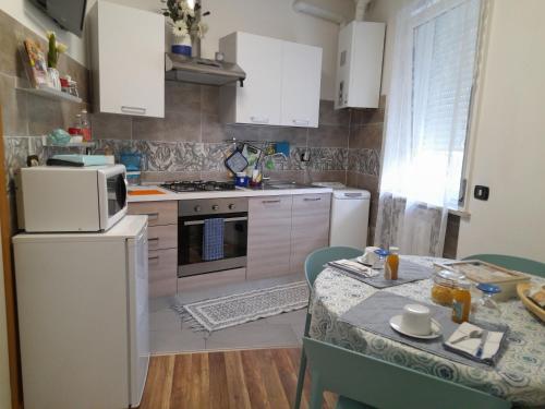 una cocina con electrodomésticos blancos y una mesa con sillas. en Cristel Malpensa apartment, en Cardano al Campo