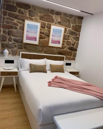 a bedroom with a large bed and a brick wall at Mar De Muros in Muros