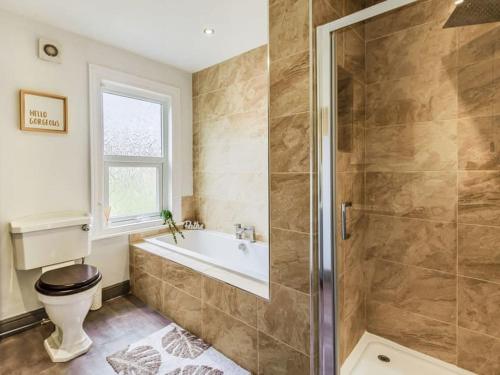 a bathroom with a tub and a toilet and a shower at Stylish Uphill Townhouse in Lincoln