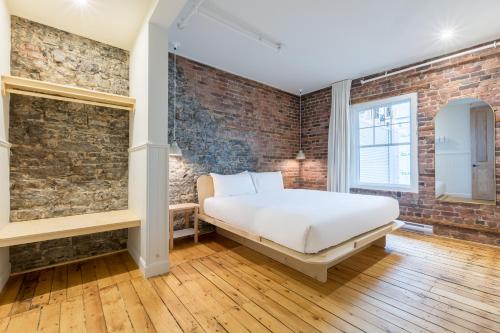 - une chambre avec un lit et un mur en briques dans l'établissement La Maison des Lofts - Par les Lofts Vieux-Quebec, à Québec