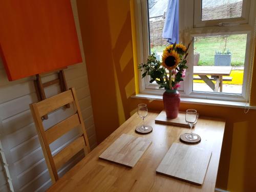 a table with two glasses and a vase of flowers on it at The Old Potting Shed with hot tub. Colan, Newquay. in Newquay
