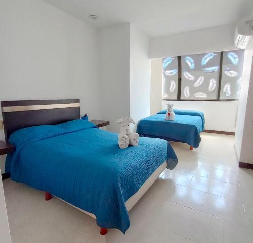 ein Schlafzimmer mit zwei Betten mit blauen Laken und Stofftieren in der Unterkunft Hotel Plaza Playa in Playa del Carmen