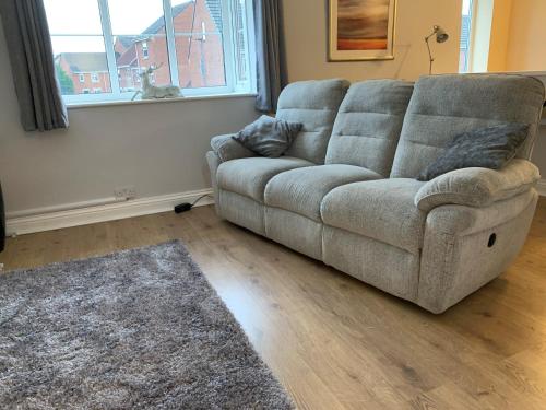 a couch sitting in a living room next to a window at Craven Cottage in Northallerton