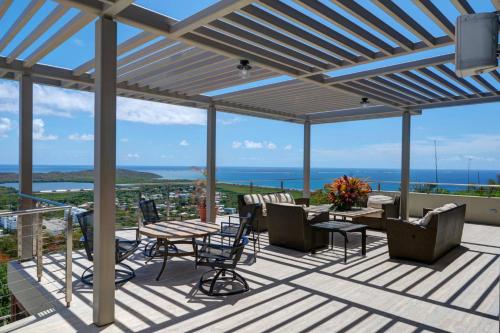 a patio with tables and chairs and a view of the ocean at Happy Days Villa A in Fajardo
