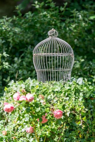 a bird cage sitting in a bed of flowers at Domaine de la Course in Doudeauville