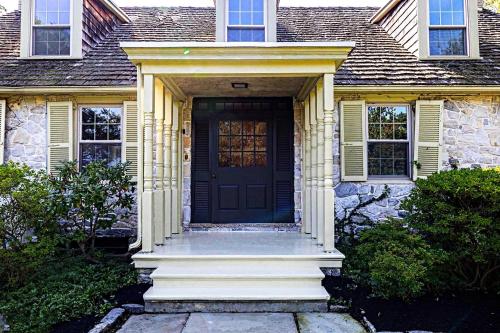 uma porta da frente de uma casa com uma porta preta em Downingtown Manor - 1900s Farmhouse with Creek Views em Downingtown