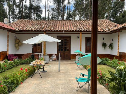 ein Haus mit einem Regenschirm, einem Tisch und Stühlen in der Unterkunft CasaHotel Laguna Jauja Airport in Jauja