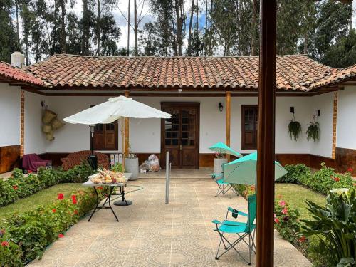 a house with an umbrella and a table and chairs at CasaHotel Laguna Jauja Airport in Jauja