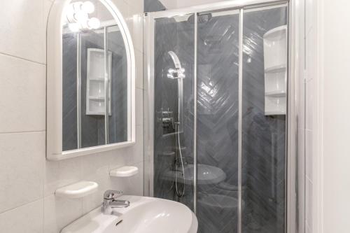 La salle de bains blanche est pourvue d'une douche et d'un lavabo. dans l'établissement Appartamento Vert, à Diano Marina
