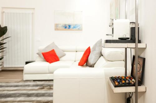 a white living room with a white couch and red pillows at Verona Suites in Verona