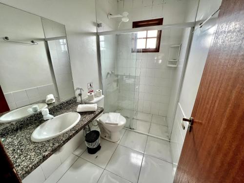 a bathroom with a sink and a toilet and a mirror at Búzios Flat Pousada in Búzios