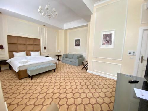 um quarto com uma cama, um sofá e um lustre em Venetian Bucharest em Bucareste